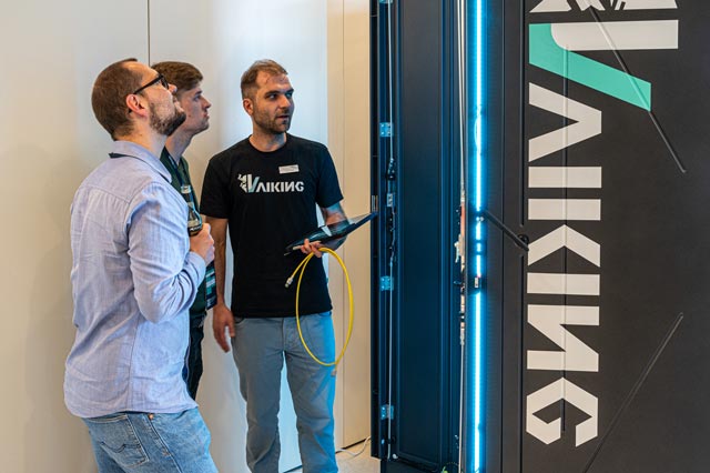 Besucher im Gespräch vor Serverrack Vaiking